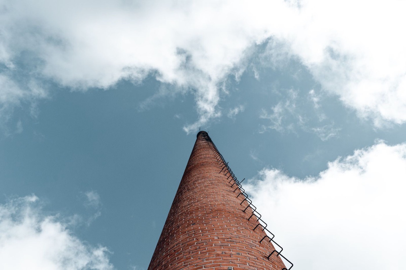 Ladder set up against a brick chimney under a blue sky for a close inspection